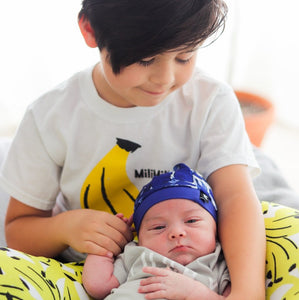 Kid in MiliMili Banana Tee holding baby sister wearing MiliMili Baby Beanie