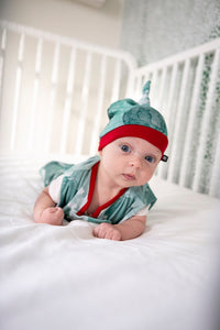baby wearing milimili teal and red holiday bubbles sleep sack and bamboo baby beanie 