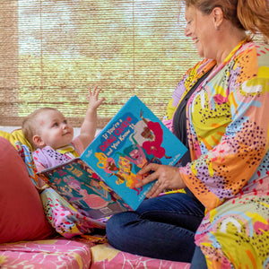 Adorable baby with Modern Rainbow print lovey by MiliMili, in collaboration with Pronoun by Jesse Tyler Ferguson and Mom reading If You're a Drag Queen and You Know It