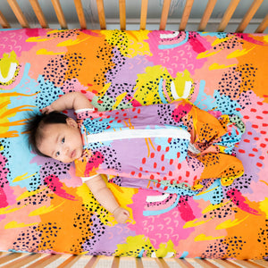 Pronoun by Jesse Tyler Ferguson modern rainbow crib sheet, by MiliMili. With adorable baby in matching sleep sack. 