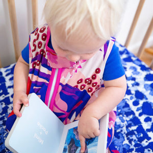 Baby reading book in crib, on milimili playa blue tie dye sheet. the best crib sheets for sensitive skin
