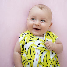 Load image into Gallery viewer, baby in crib, wearing banana print sleep sack with contrasting neon coral zipper. the most giftable baby goods, safe bamboo sleep sack, safe sleep sack