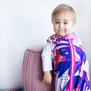 Baby wearing puebla rosa sleep sack, floral design featuring pinks, navy, and purple with pink trim. The best sleep sacks for summer.
