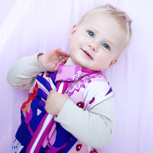 Baby wearing puebla rosa sleep sack, floral design featuring pinks, navy, and purple with pink trim. The best sleep sacks for summer. safe bamboo sleep sack, safe sleep sack
